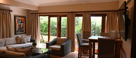 A spacious living room with a sofa, chairs, a table, and a TV.