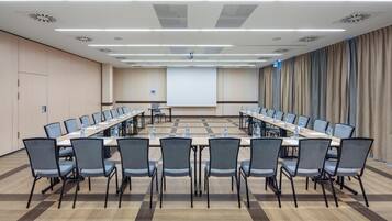 A conference room with a long table, multiple chairs, and a projector screen.
