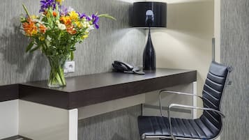 Un comptoir d’accueil moderne, avec un vase de fleurs, un téléphone et une chaise noire.