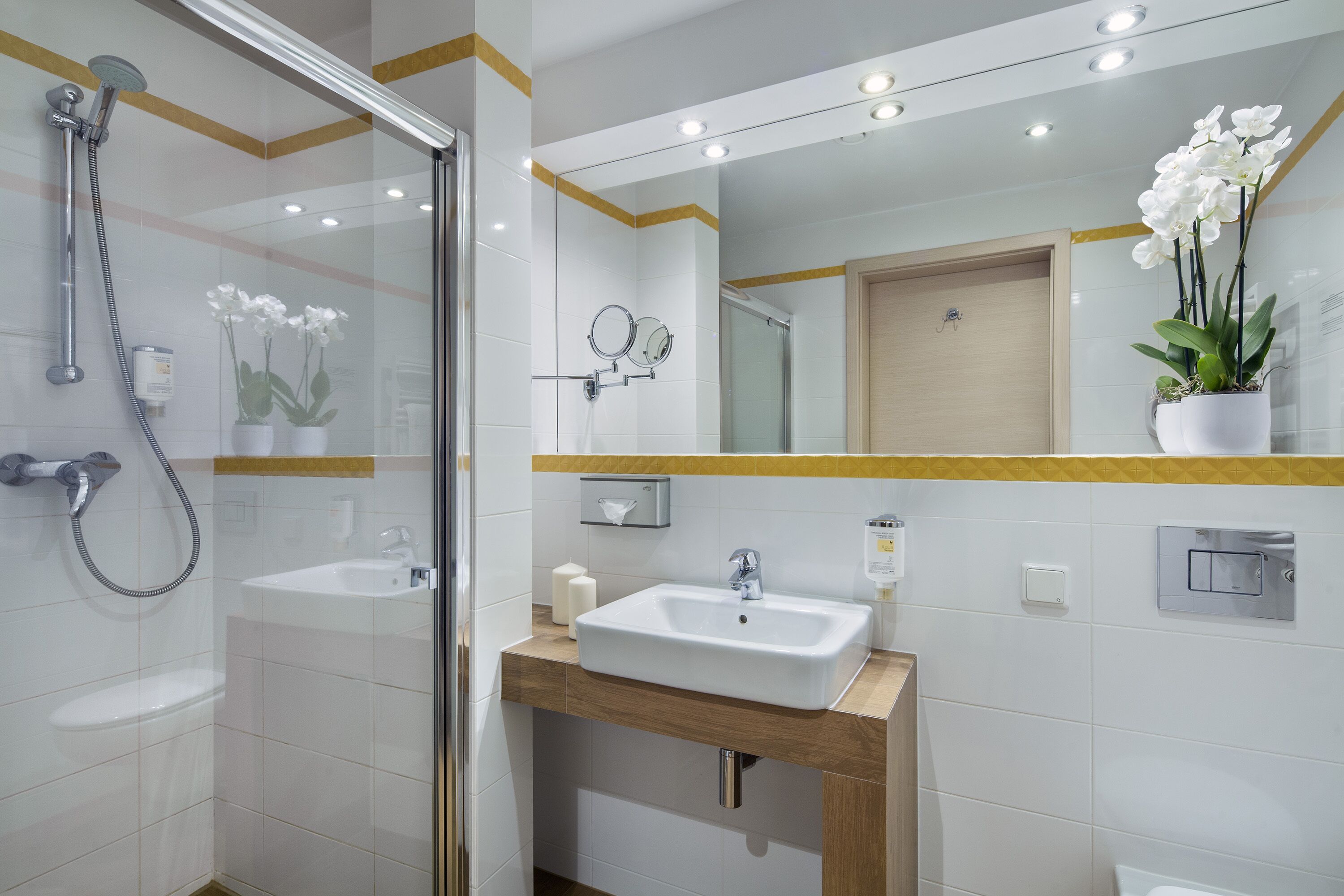 A modern bathroom with a glass-enclosed shower, a sink with a wooden countertop, and a mirror above the sink.
