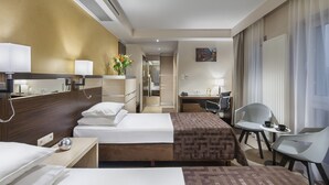 Una habitación de hotel con dos camas, un escritorio, una silla y una mesita.