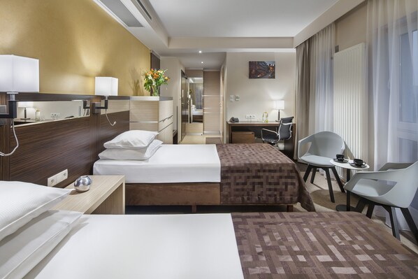 Una habitación de hotel con dos camas, un escritorio, una silla y una mesita.