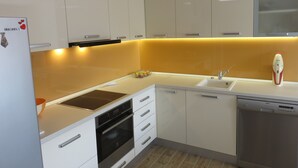 A modern kitchen with white cabinets, a built-in oven, a dishwasher, and a yellow accent wall. - Apartments Istarska - Adults Only (Split)