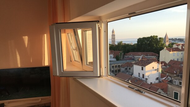 A room with a window overlooking a cityscape, including a prominent tower. - Apartments Istarska - Adults Only (Split)