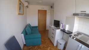 A compact living space with a sofa, kitchenette, and a television. - Apartments Istarska - Adults Only (Split)