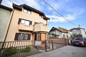 Un immeuble résidentiel de deux étages, avec une façade beige, des volets marron et une porte en bois.