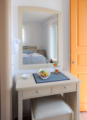 A white vanity with a mirror, a bowl of fruit, and a small plant. - Aigaio Studios Tinos (Tinos)