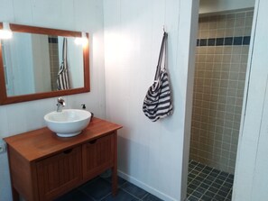 A bathroom with a white sink, wooden vanity, and a striped towel hanging on the wall. - Les Hôtes du Paradis (Forges)