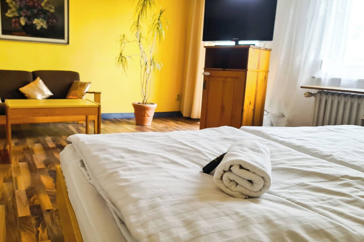 Ein Hotelzimmer mit Bett, Sofa, Blumentopf und Fernseher.