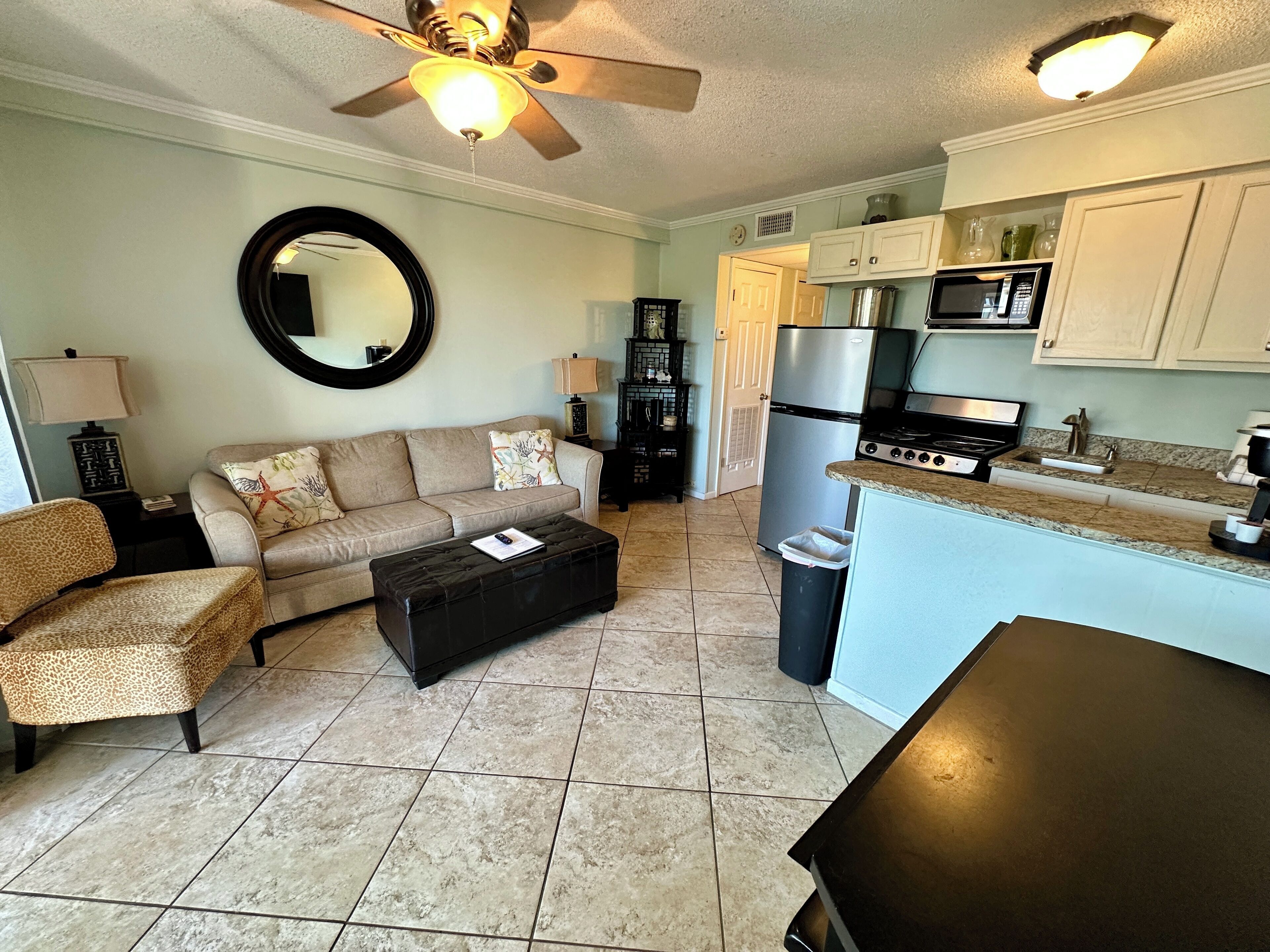 A living room with a sofa, coffee table, and a dining area with a kitchen in the background.
