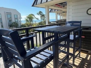 A deck with a table and chairs, overlooking a body of water and buildings.
