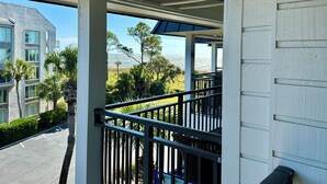 A balcony with a view of a coastal landscape, including trees and a building in the background. - Beach Happy!-Nice ocean view Hilton Head Villa (Hilton Head Island)