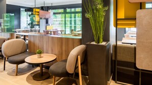 A modern interior with a reception desk, seating area, and large windows. - B&B HOTEL Paris Meudon Vélizy (Meudon)
