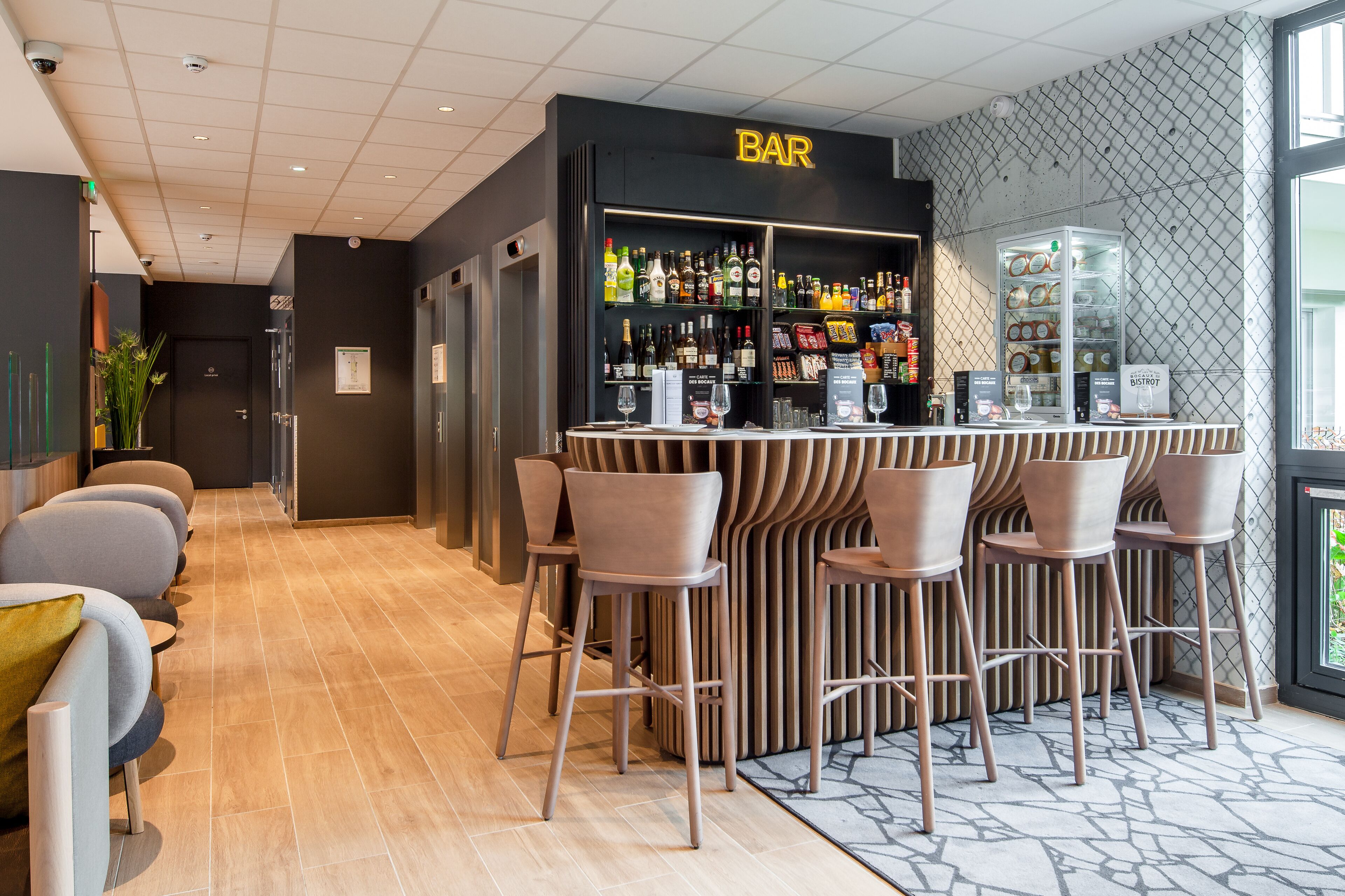 A bar area with a counter, stools, and a variety of bottles and glasses.