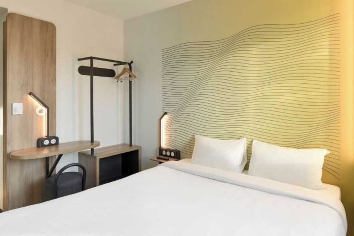 Een moderne hotelkamer met een bed, een bureau en een wandplank.