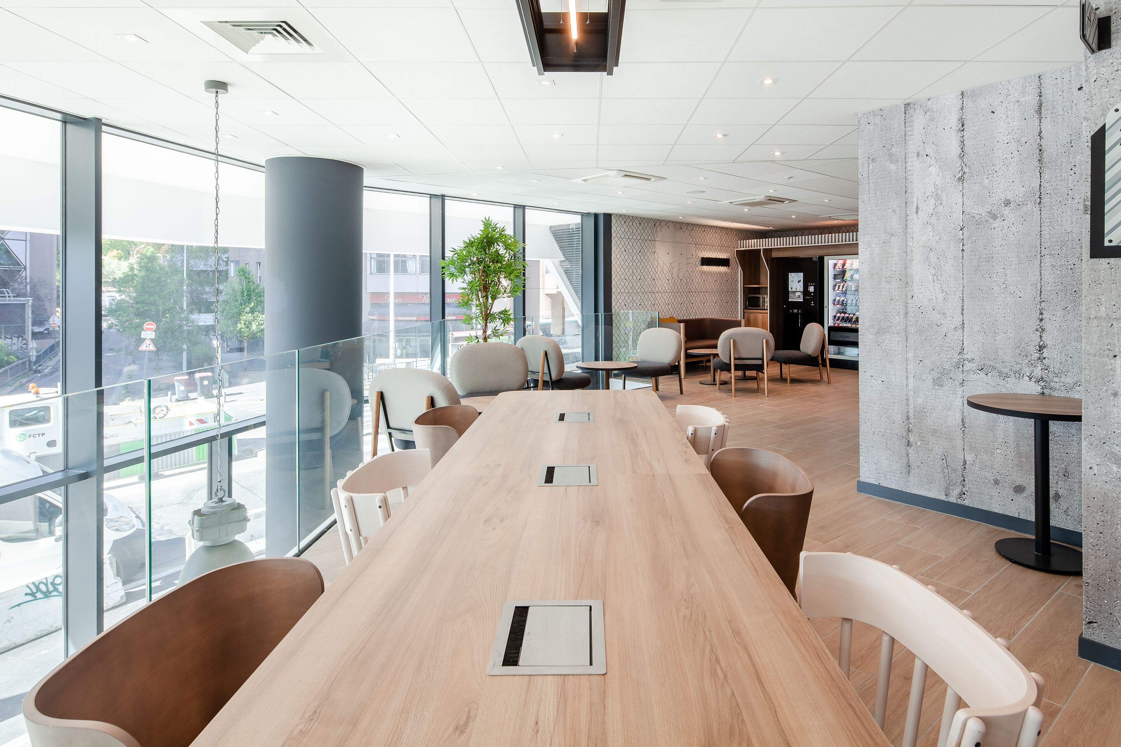 Une salle de conférence moderne, dotée d’une longue table, de chaises et d’une grande fenêtre donnant sur un panorama urbain.