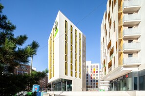Contemporary building with a striking vertical design, featuring windows and balconies.