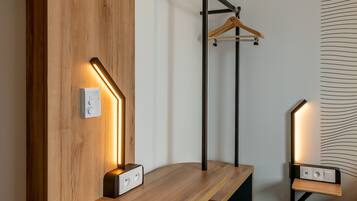 A modern room with a wooden accent wall, a hanging light fixture, and a wooden bench with a built-in charging station.