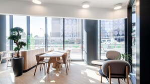 Un espacio de oficina moderno con ventanas amplias, un mostrador de recepción y varias áreas de estar.