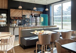 Un ristorante moderno con area bar, posti a sedere e vista all'esterno.