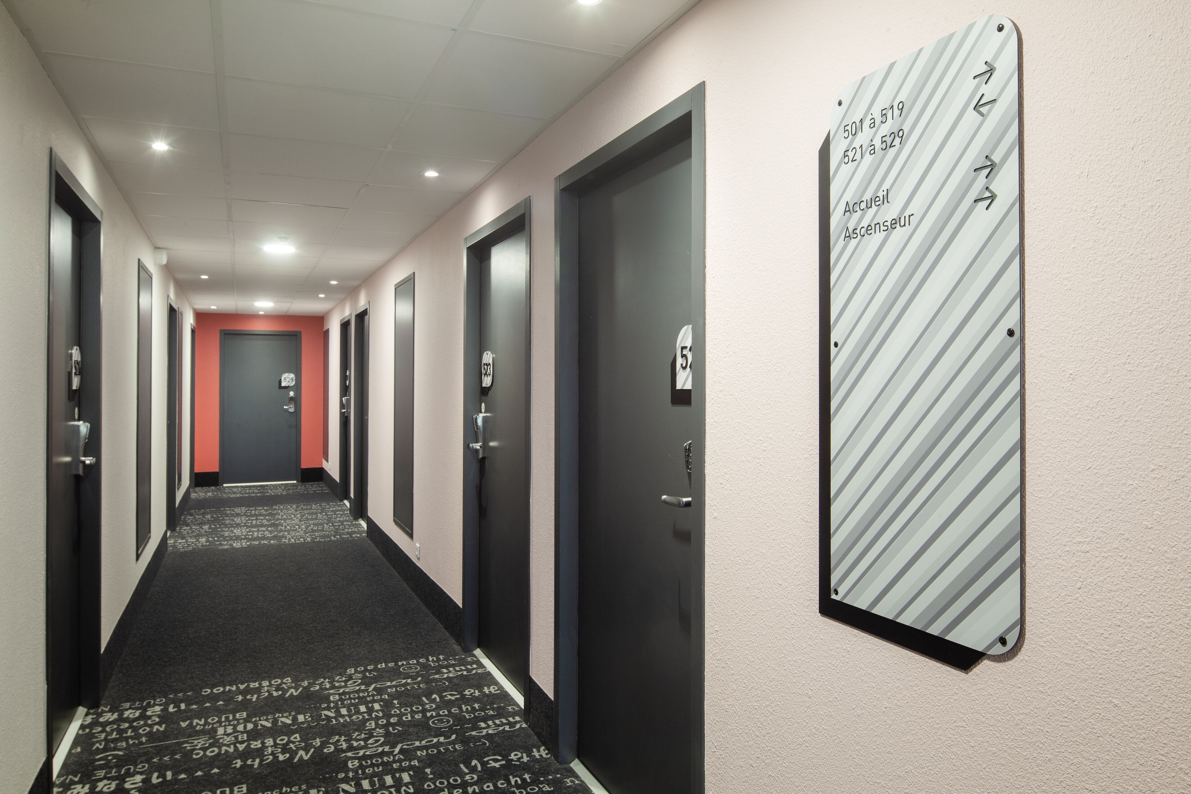 Pasillo de hotel con puertas numeradas del 501 al 529, una zona de recepción y acceso al gimnasio.