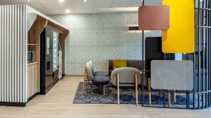 Un interior moderno con área de cocina, asientos de color amarillo y pared con estampado.