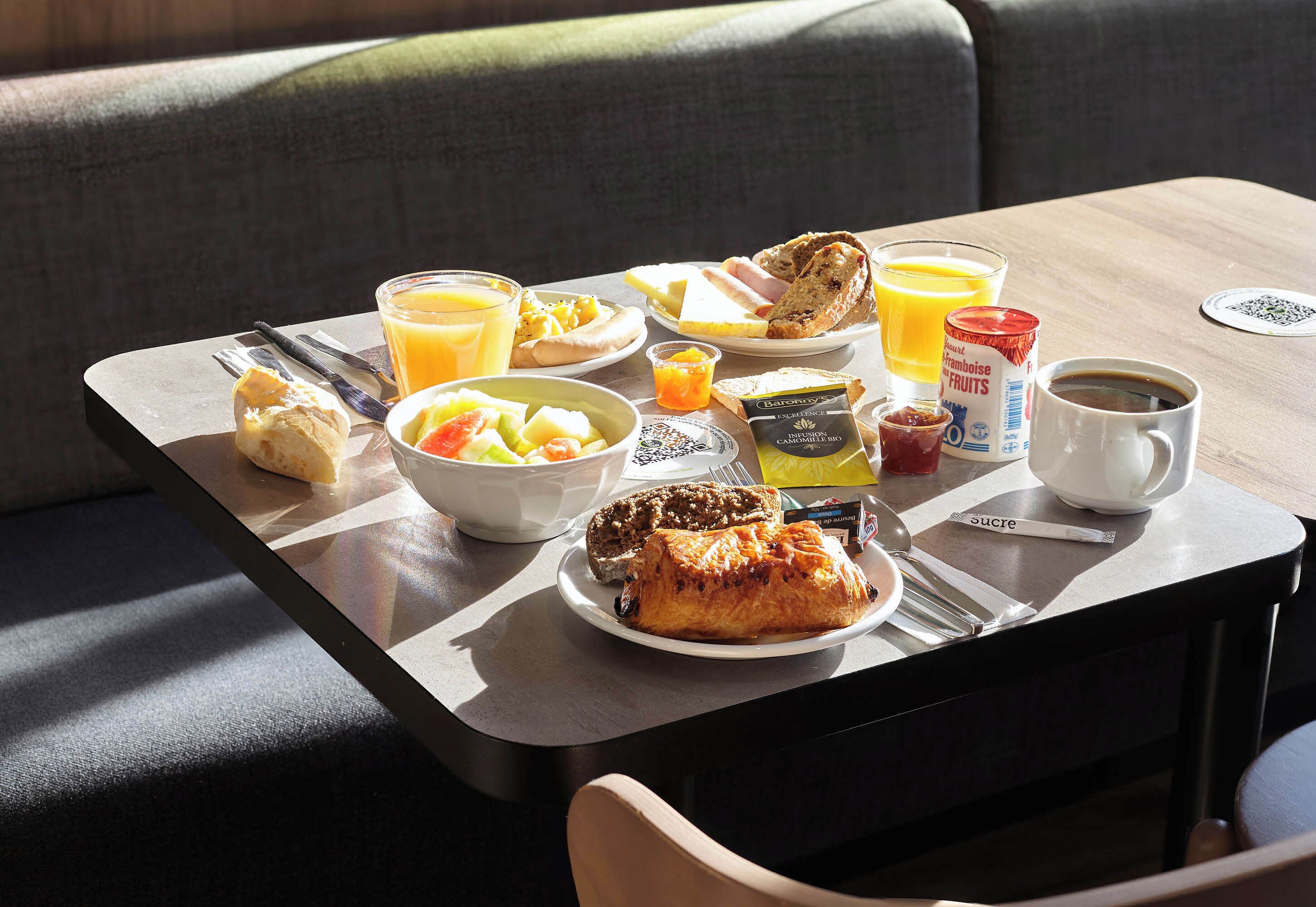 A breakfast tray with toast, fruit, juice, and coffee on a table in a room with a couch.