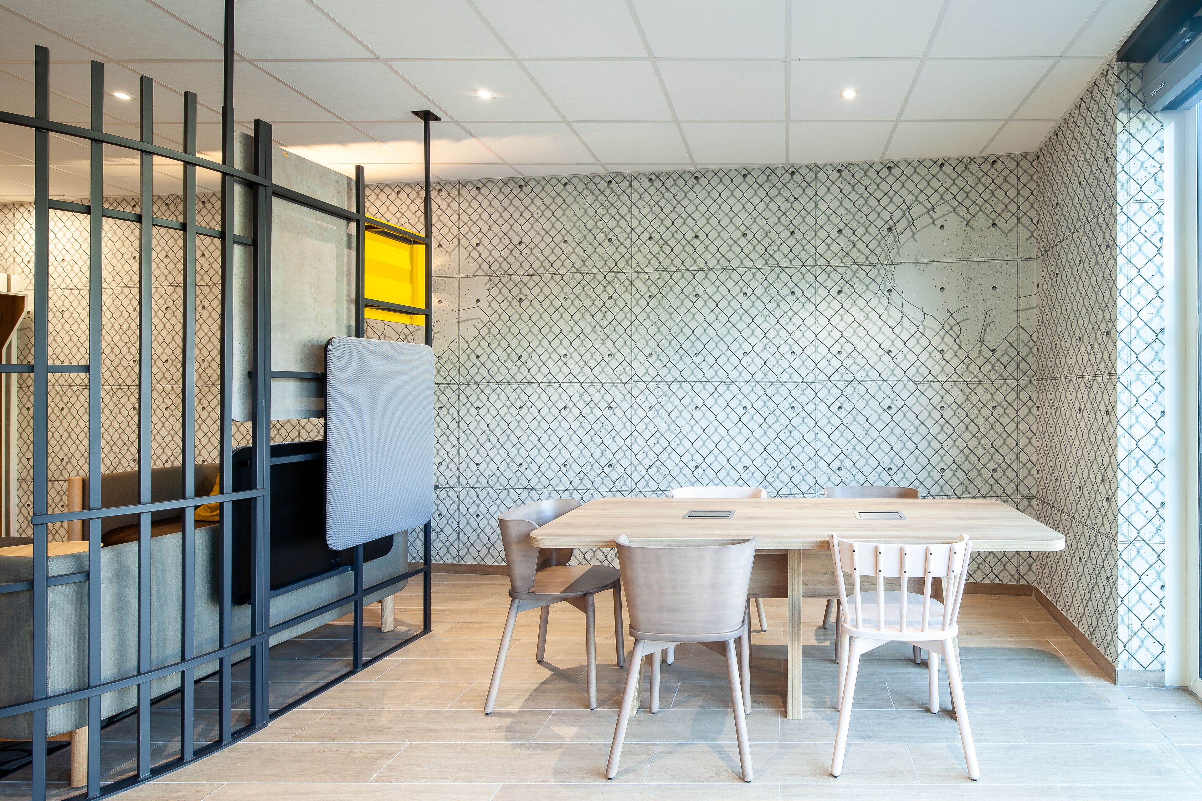 A modern meeting room with a large table, four chairs, a whiteboard, and a glass partition.