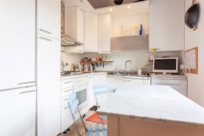 Une cuisine moderne avec des meubles blancs, un grand îlot central, une cuisinière et un lave-vaisselle.