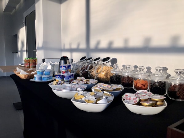 A buffet table with various food items including yogurt, cereal, and nuts.