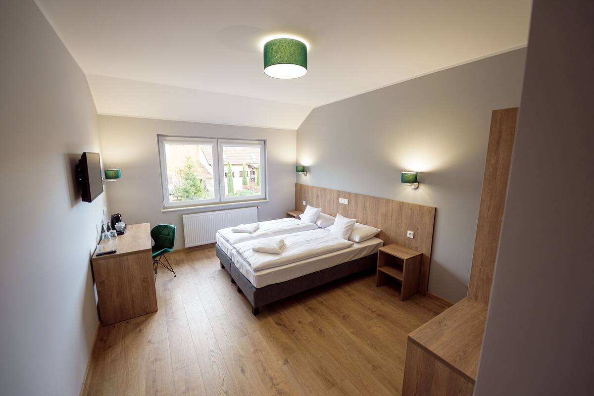 A modern bedroom with a wooden bed, bedside tables, a desk, and a chair.