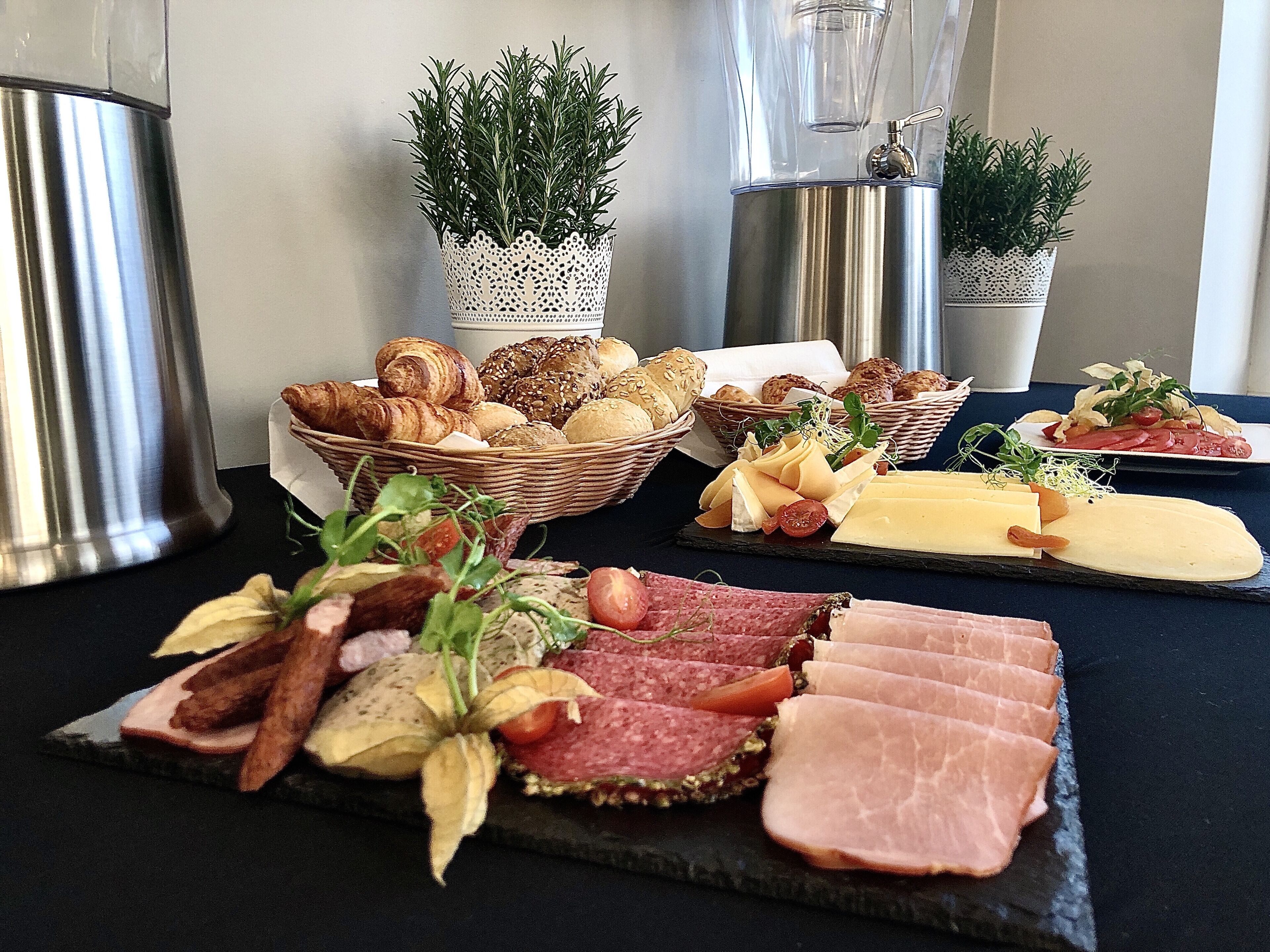Eine Auswahl an Lebensmitteln, darunter Brot, Käse und Fleisch, auf einem Tisch angerichtet.