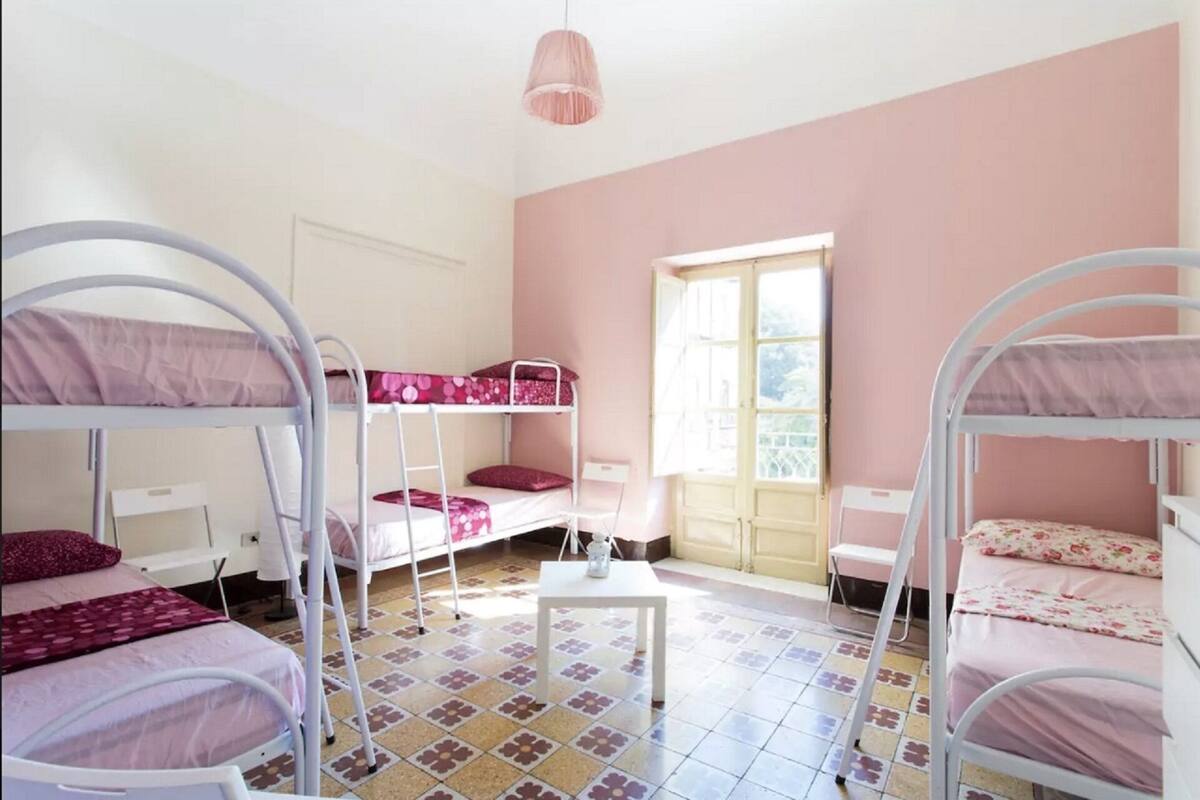 Une chambre de dortoir avec des lits superposés, une petite table et une fenêtre.