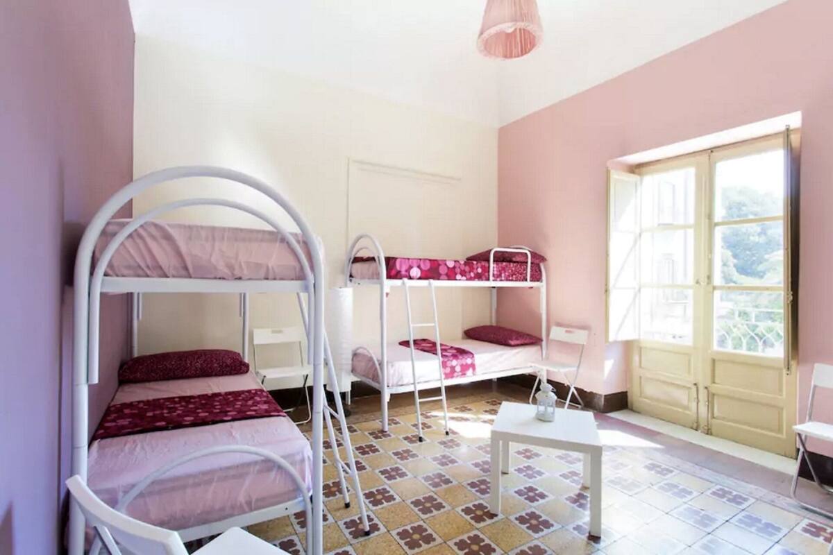 Une chambre de dortoir avec des lits superposés, une petite table et une fenêtre donnant sur un paysage agréable.