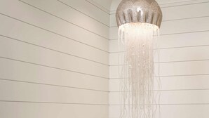 Een modern interieur met een hanglamp, een ingelijst kunstwerk en een trapleuning.