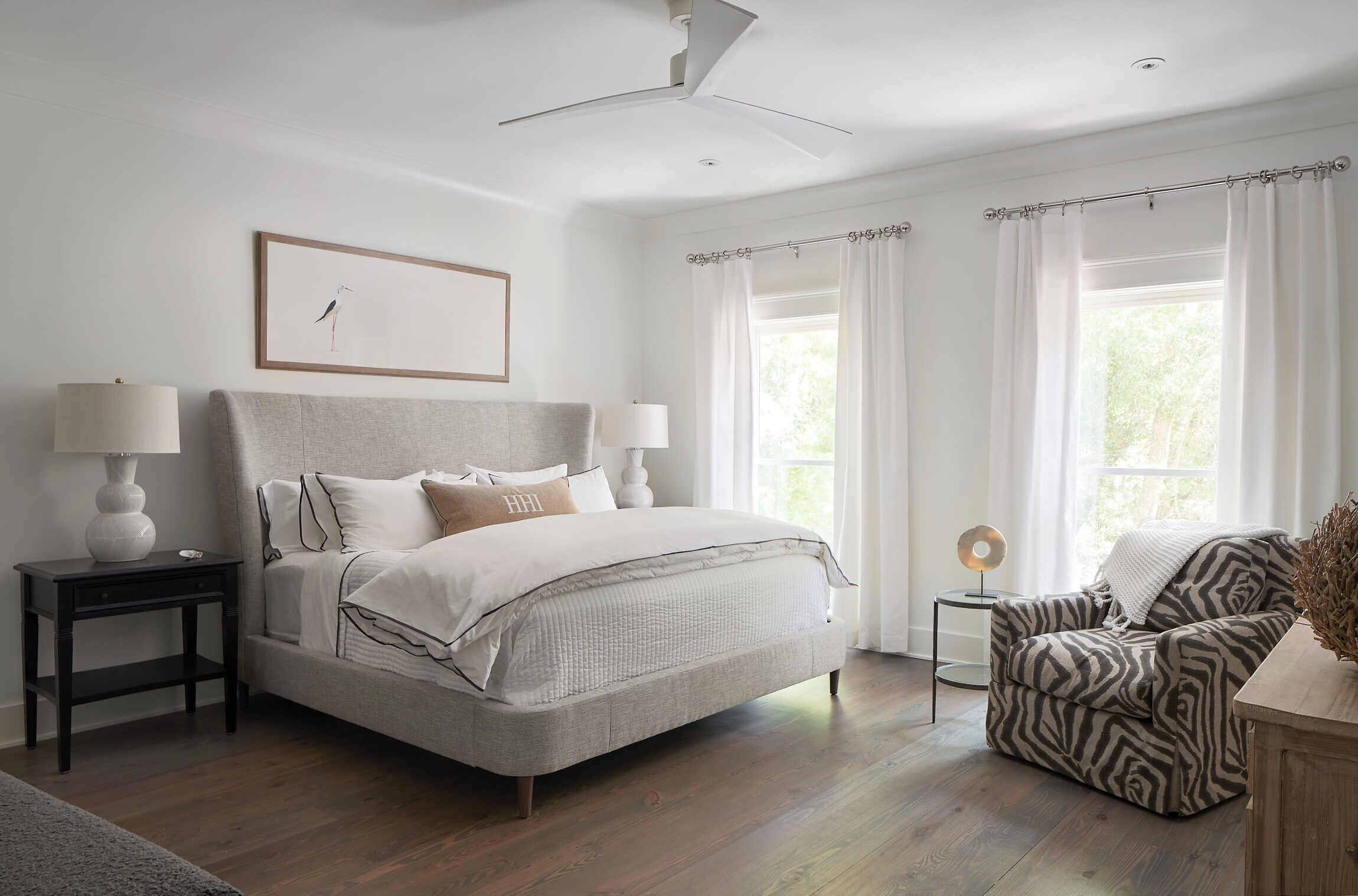 A bedroom with a bed, bedside tables, a chair, a lamp, and a picture on the wall.