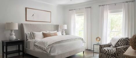 A bedroom with a bed, bedside tables, a chair, a lamp, and a picture on the wall.
