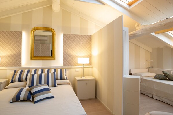 A modern bedroom with a large bed, a bedside table, a nightstand, a mirror, and a lamp.