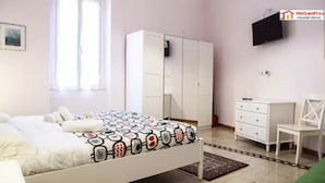 Un dormitorio con cama, armario, televisor y escritorio.