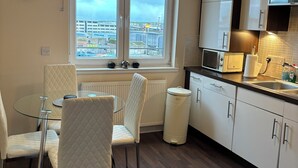 Cozinha moderna com armários brancos, micro-ondas e janela com vista para a cidade.