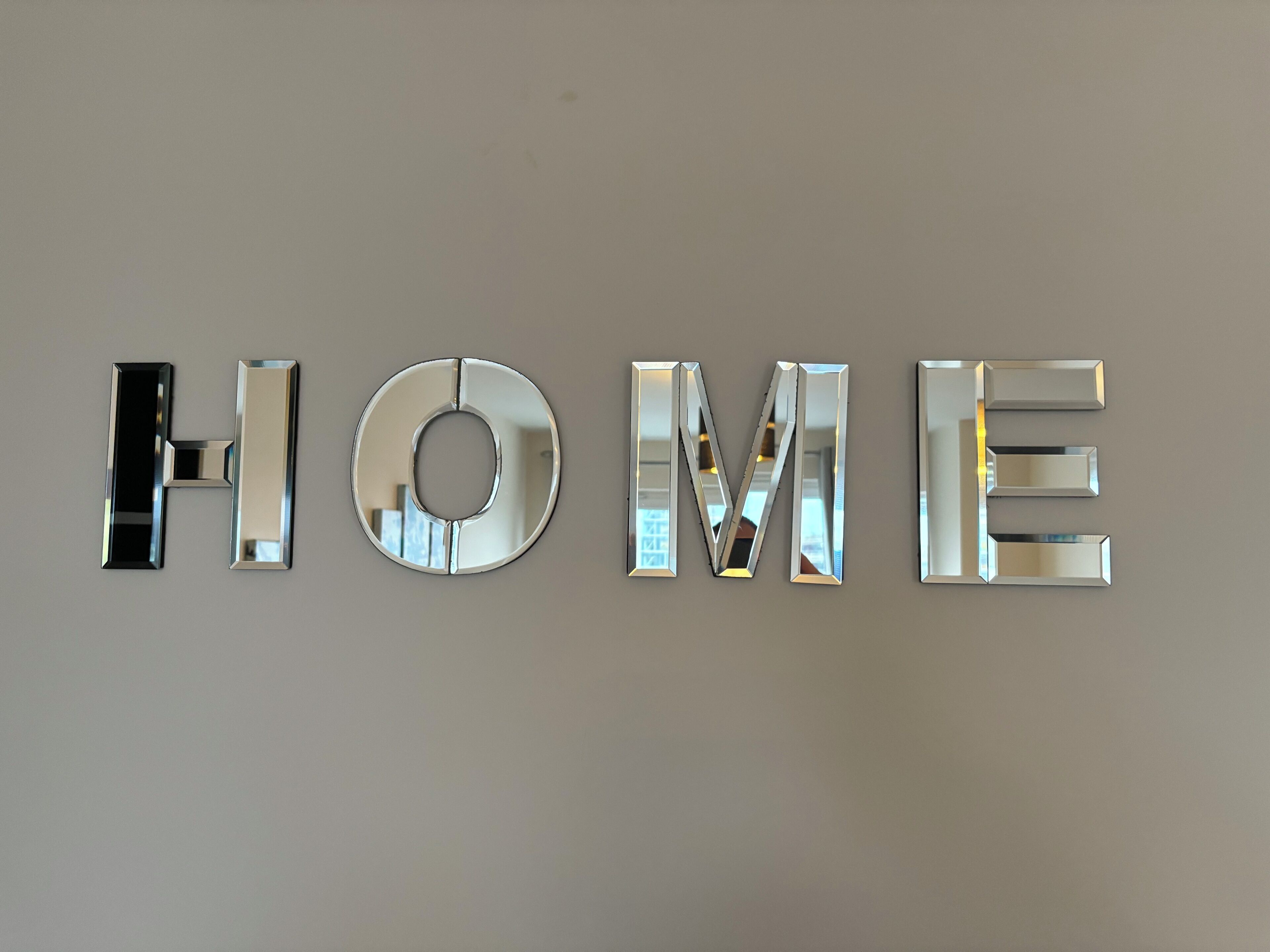 Un letrero metálico fijado a la pared que dice 'HOME' en letras reflectantes.