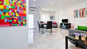 A modern living room with a dining area, a sofa, a TV, and artwork on the walls. - Maison Roberta (Rome)