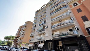 A multi-story residential building with balconies, air conditioning units, and a storefront with signage. - Maison Roberta (Rome)