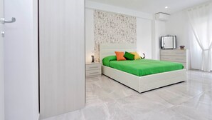 A modern bedroom with a large bed, a nightstand, a dresser, and a mirror. - Maison Roberta (Rome)