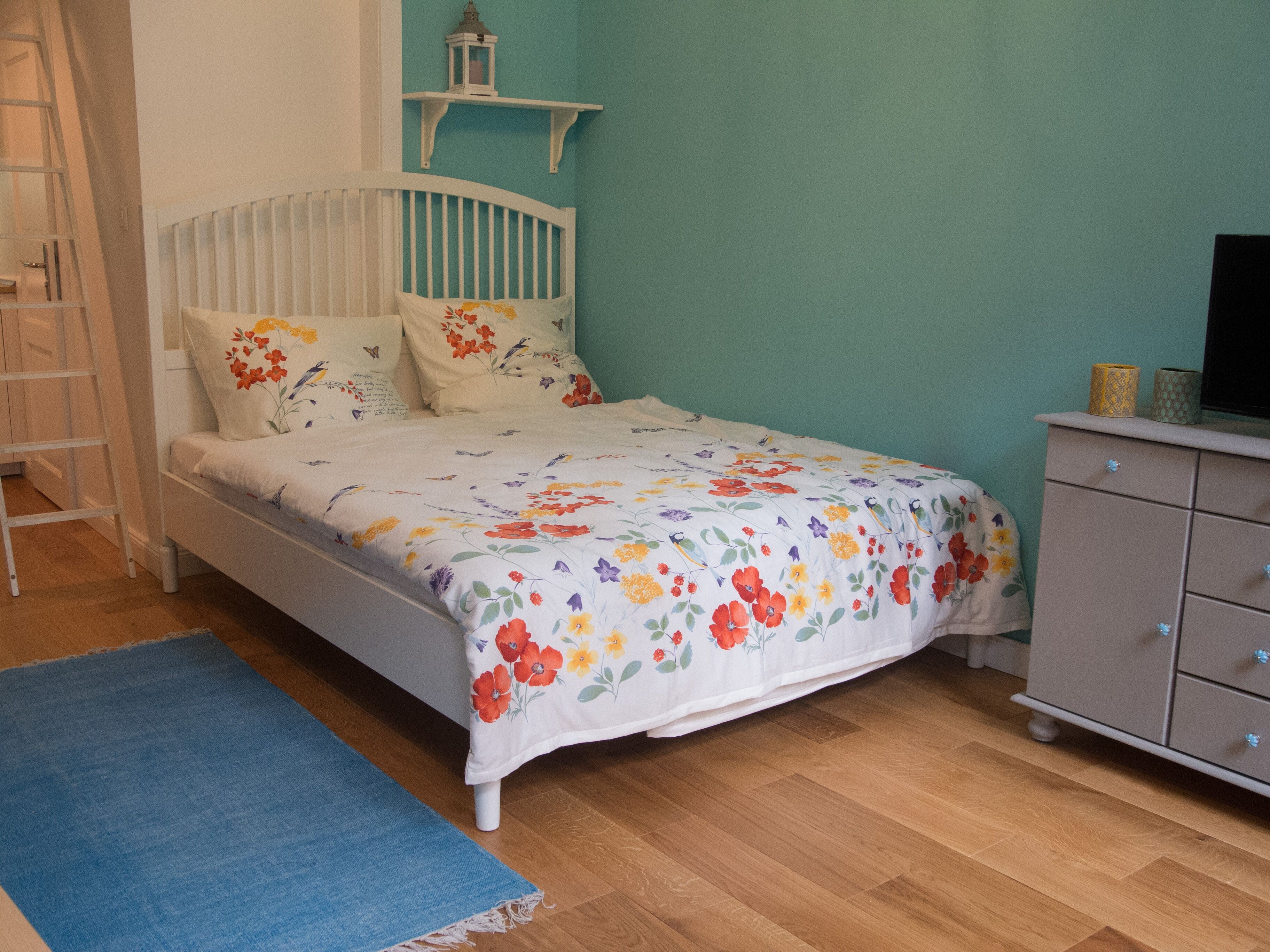 Une chambre à coucher avec un lit, une commode et un tapis bleu.