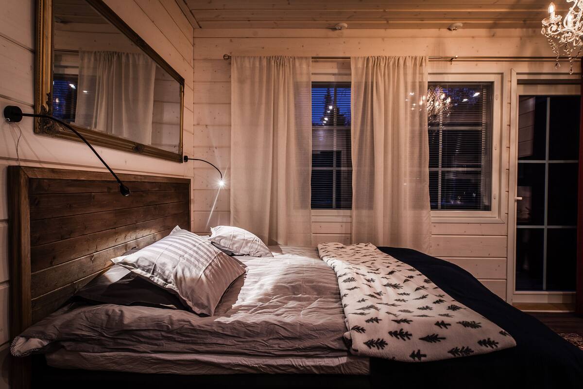 A bedroom with a wooden headboard, a large mirror, and a bed with multiple pillows.