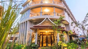 A multi-story building with a curved facade, balconies, and a well-lit entrance. - Family room: 1double & single bed - free breakfast (Kok chock commune)