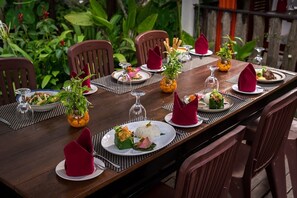 A dining table set with plates of food, glasses, and red napkins.
