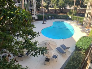 A swimming pool with lounge chairs and umbrellas, surrounded by trees and a fence. - Gone Coastal! 2 from oceanfront! Central air! (Hilton Head Island)
