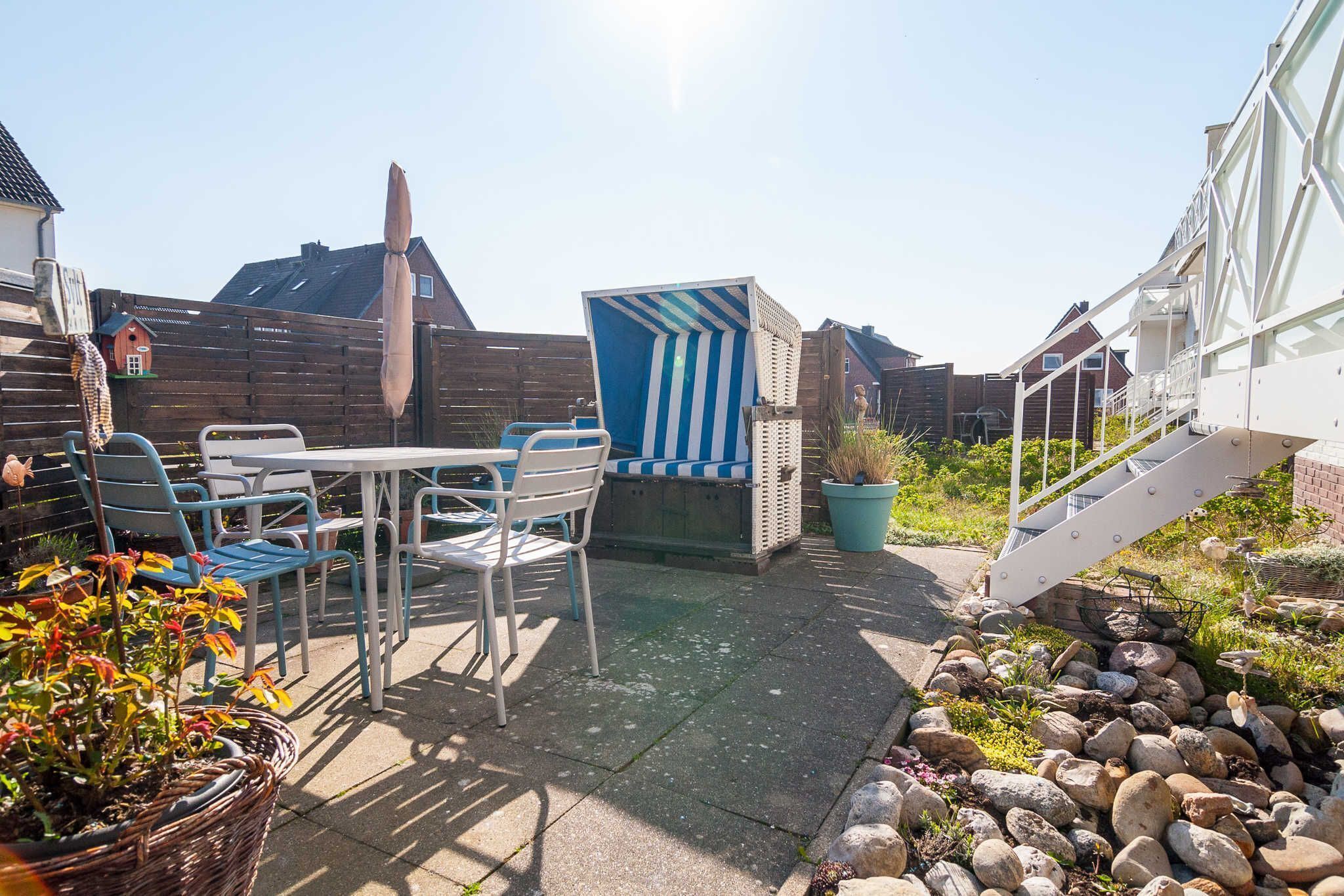 A patio with a table and chairs, a blue and white striped structure, and a wooden fence.